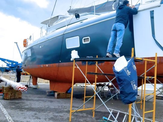 Dois Ninjas a aplicar vinil num catamarã