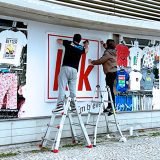 dois Ninjas a aplicar vinil numa montra Decoração de montras