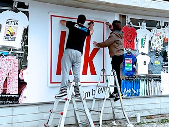 dois Ninjas a aplicar vinil numa montra Decoração de montras